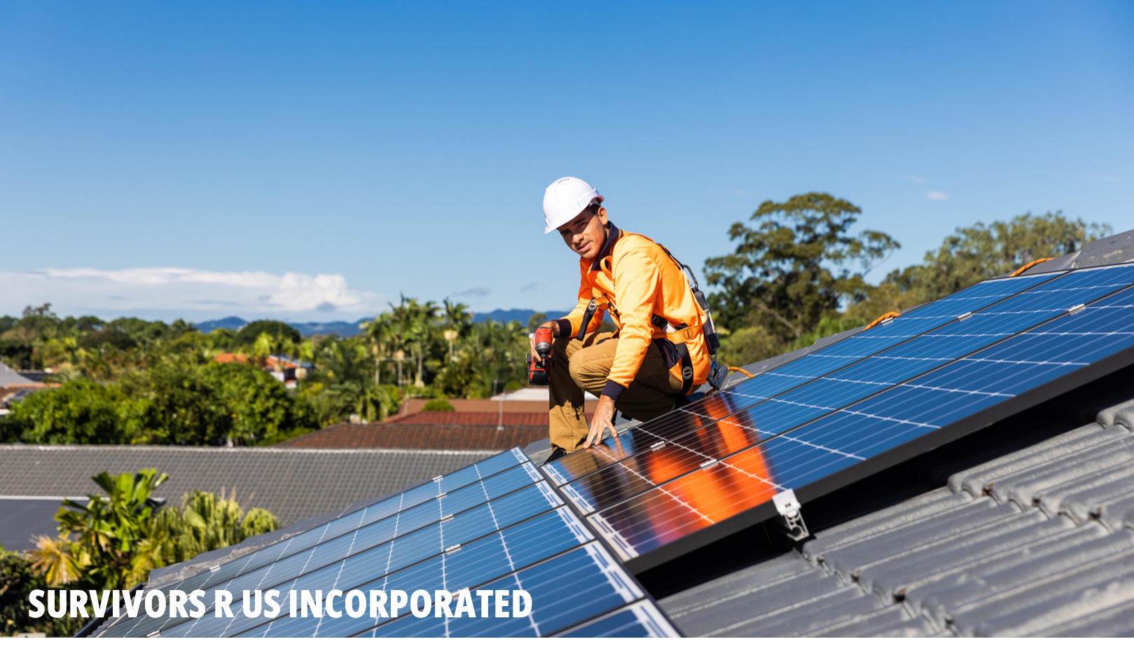 Survivors R Us picture showing a man in hard hat and hi-vis installing solar panels on a house roof. There are green trees and a blue sky in the background.