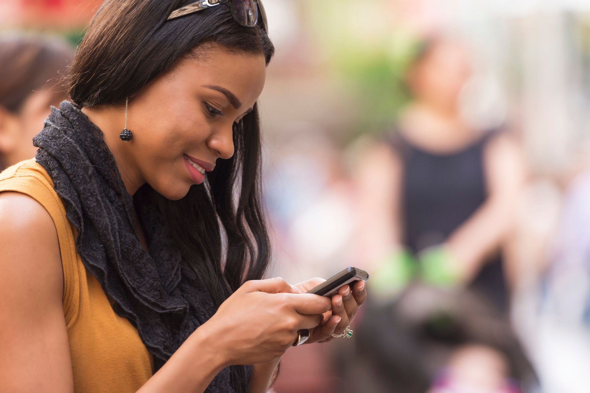 Mixed race Australian woman smiling and texting on her smartphone.