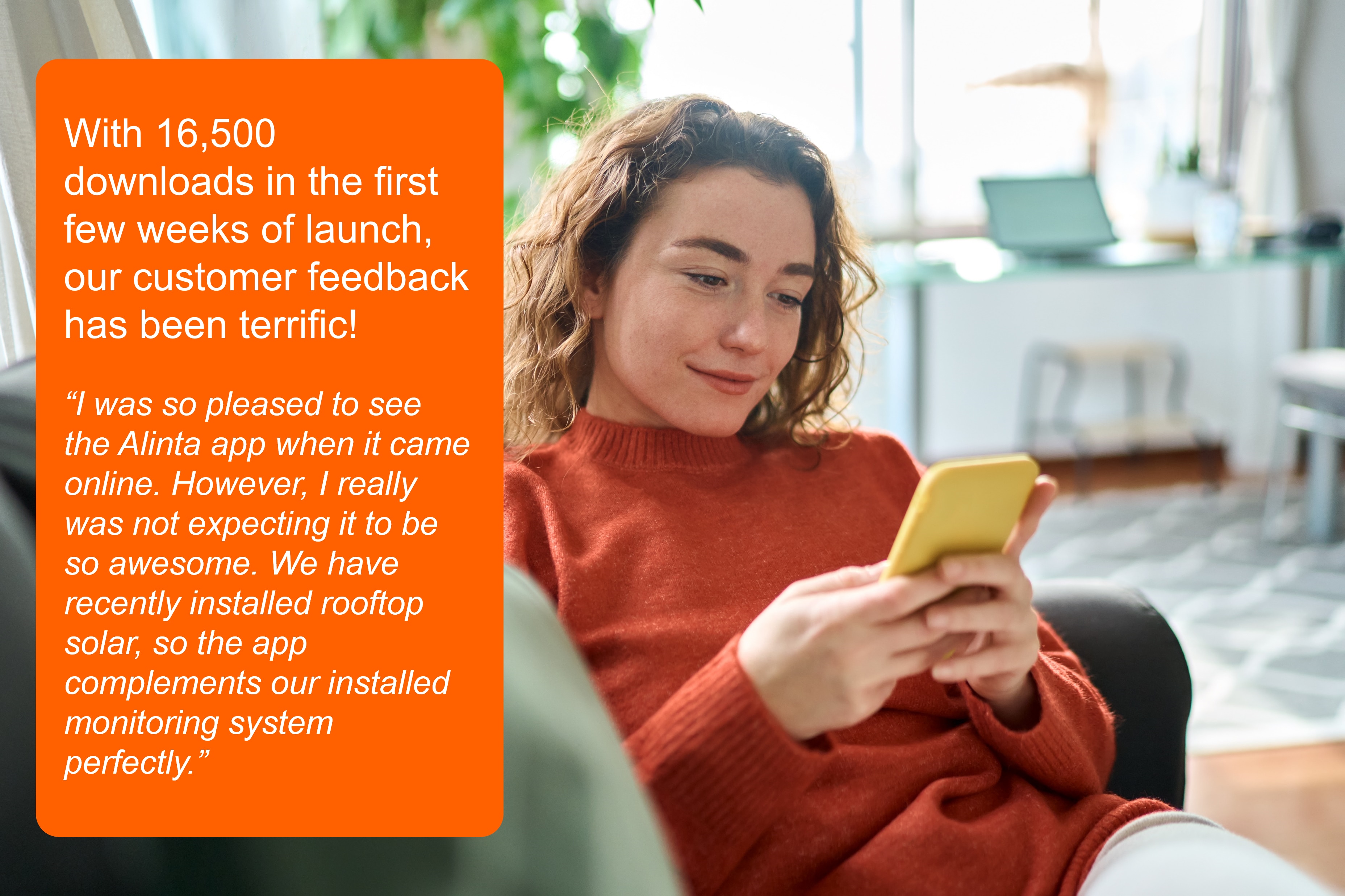 A young, smiling woman relaxes on her couch holding her phone. To the left of her is white text on an orange rectangular background reading: With 16.5K downloads in the first few weeks of launch, our customer feedback has been terrific!   “I was so pleased to see the Alinta app when it came online. However, I really was not expecting it to be so awesome. We have recently installed rooftop solar, so the app complements our installed monitoring system perfectly.”  