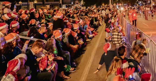 Crowds of people wearing Christmas hats watching the pageant on the streets of Perth