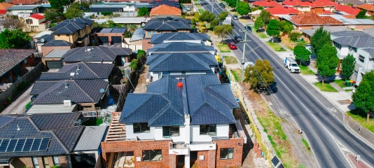 Aerial view of house rooftops in a suburb with road running alongside